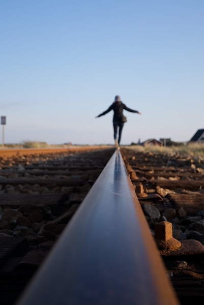 A woman balancing on a rail line.